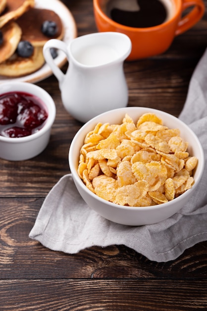 Alto angolo di corn flakes per la colazione in una ciotola con latte e marmellata