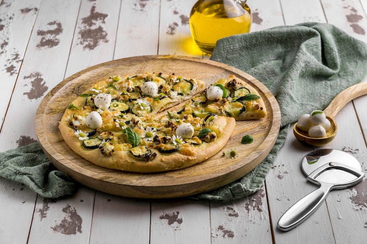 Foto gratuito alto angolo di deliziosa pizza cotta con fiori di camomilla e taglierina