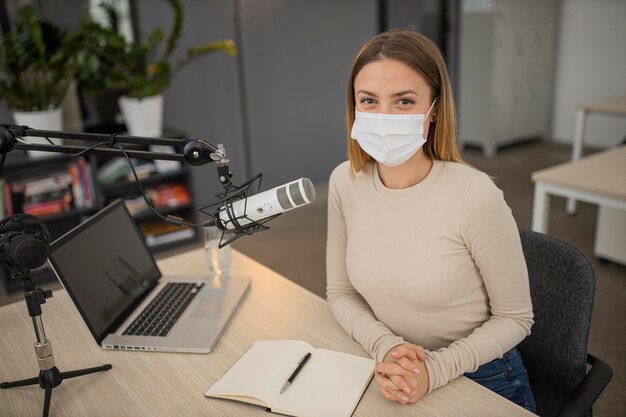 Alto angolo di donna con mascherina medica in studio radiofonico