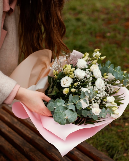 Alto angolo di donna elegante con bouquet di fiori all'aperto