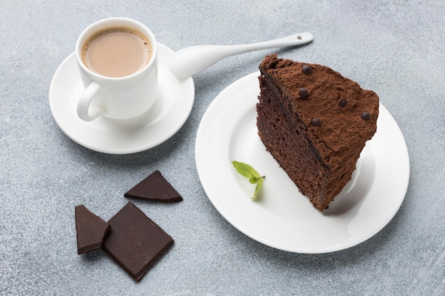 Alto angolo di fetta di torta al cioccolato sulla piastra con caffè