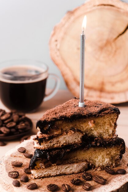 Alto angolo di fetta di torta con candela e caffè