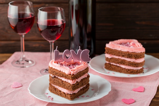 Alto angolo di fette di torta a forma di cuore con bicchieri di vino