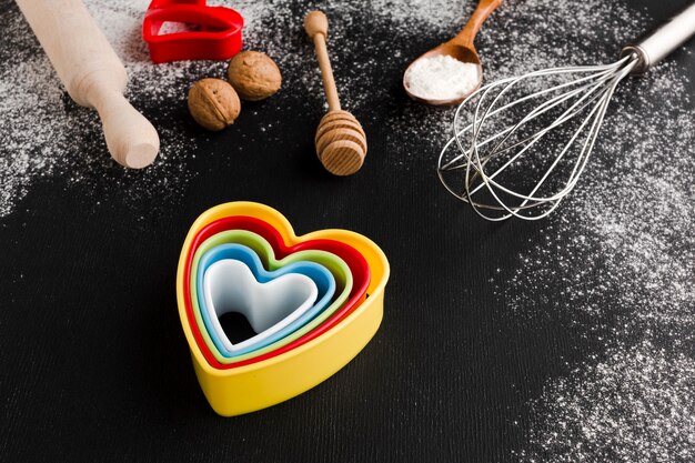 Alto angolo di forme colorate di cuore con utensili da cucina