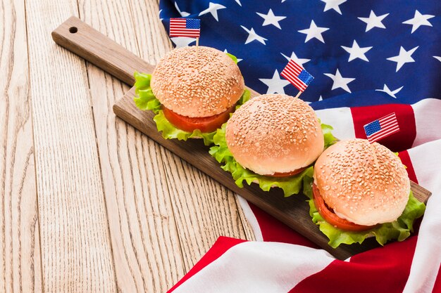Alto angolo di hamburger con bandiere americane su superficie di legno