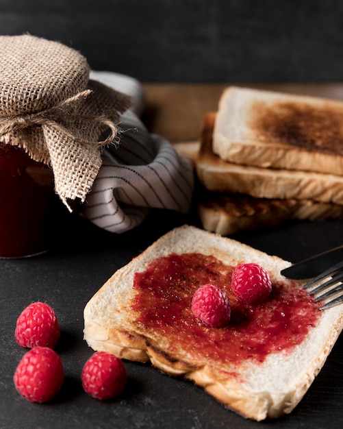 Alto angolo di marmellata di lamponi su pane con il barattolo