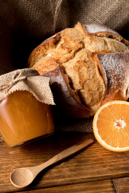 Alto angolo di pane con barattolo di marmellata di arance