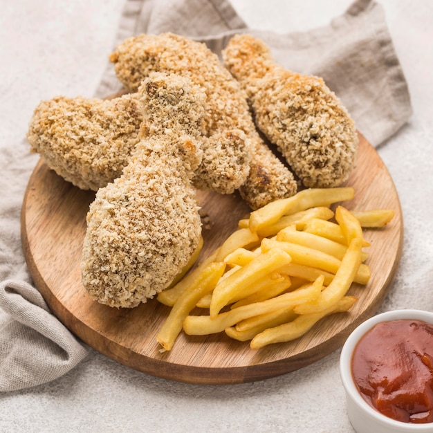 Alto angolo di patatine fritte con cosce di pollo fritte e salsa