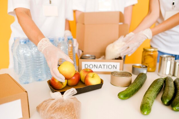 Alto angolo di persone che mettono cibo nella scatola di donazione