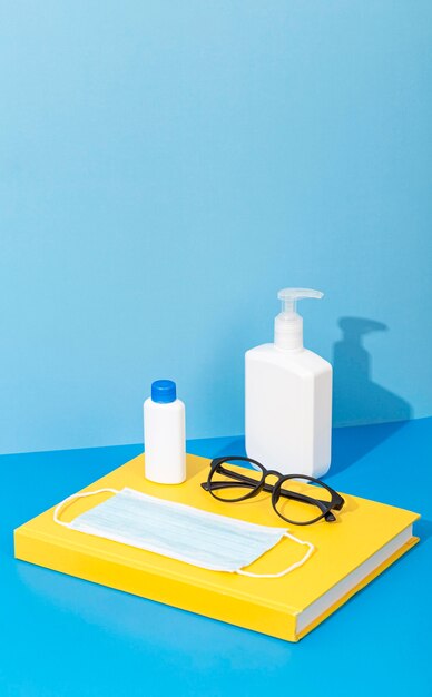 Alto angolo di ritorno a materiale scolastico con libro e disinfettante per le mani