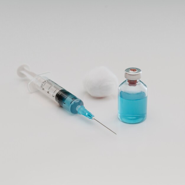 Alto angolo di siringa con cotone e bottiglia di vaccino