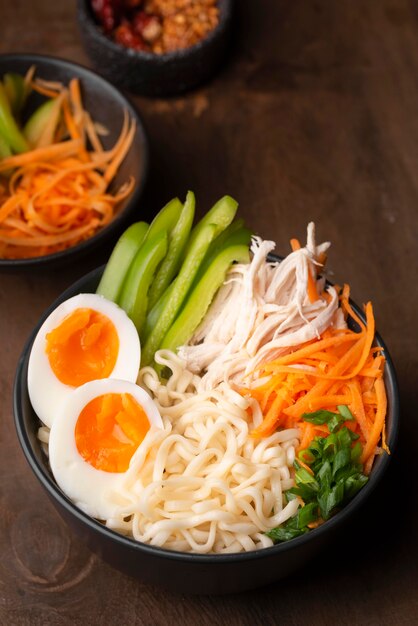 Alto angolo di tagliatelle asiatiche con uova e varietà di verdure