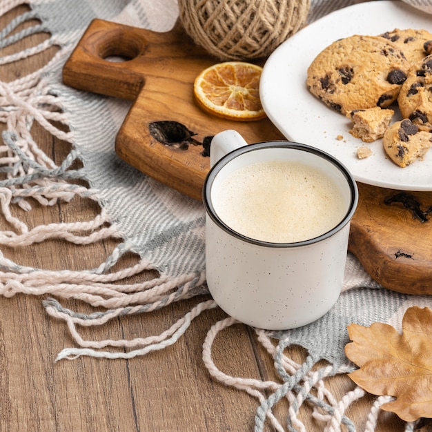 Alto angolo di tazza di caffè con biscotti e coperta