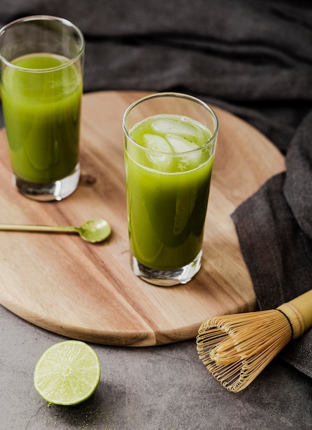 Alto angolo di tè matcha in bicchieri con cubetti di ghiaccio e lime