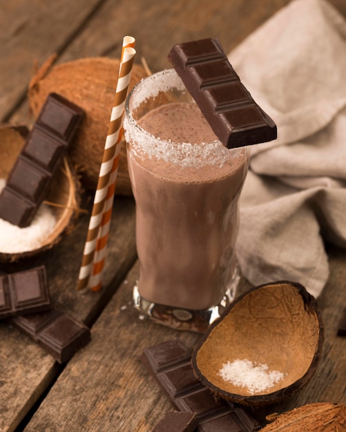 Alto angolo di vetro frappè sul vassoio con cocco al cioccolato