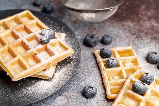 Alto angolo di waffle con mirtilli e ricoperto di zucchero a velo