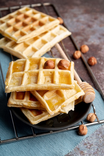 Alto angolo di waffle su piastra con mestolo di miele e nocciole