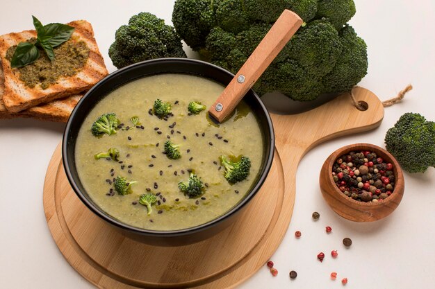 Alto angolo di zuppa di broccoli invernali nella ciotola con cucchiaio e pane tostato