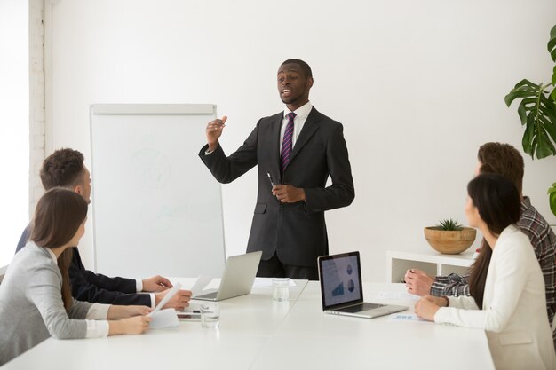 Altoparlante o business coach africano sicuro che dà presentazione alla squadra