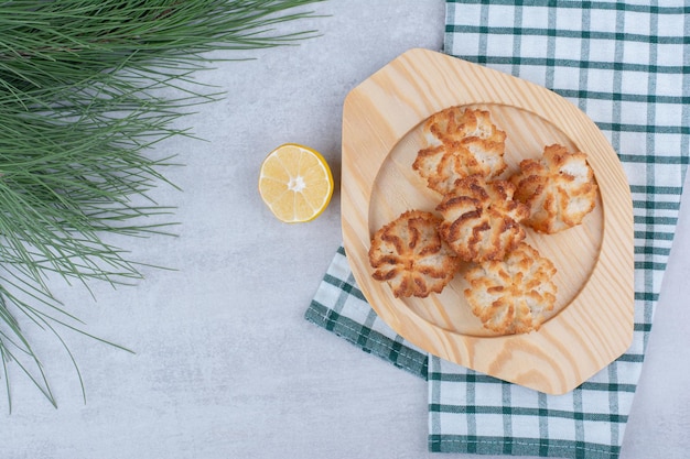 Amaretti al cocco sul piatto di legno con mezzo limone tagliato. Foto di alta qualità