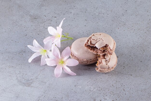 Amaretti marroni cremosi con fiori pastello sul tavolo di marmo.