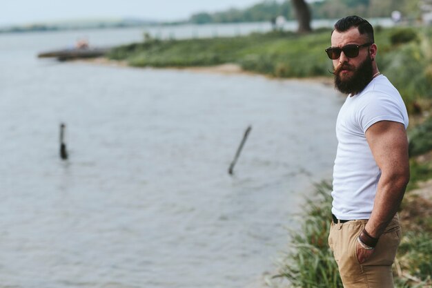 American Bearded Man guarda la riva del fiume con una giacca blu