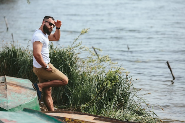 American Bearded Man guarda la riva del fiume con una giacca blu