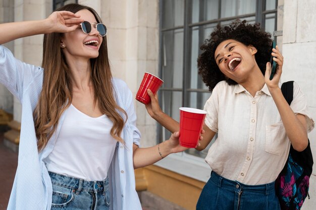 Amiche che si divertono insieme all'aperto con bicchieri di plastica