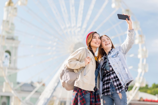 Amiche di angolo basso che prendono selfie