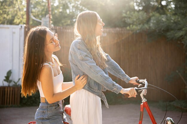 Amiche di vista laterale che guidano insieme bici