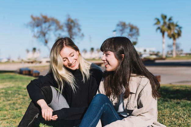 Amiche graziose che chiacchierano sull&#39;erba verde