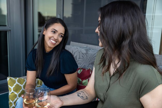 Amiche sorridenti che trascorrono del tempo insieme e bevono vino su una terrazza