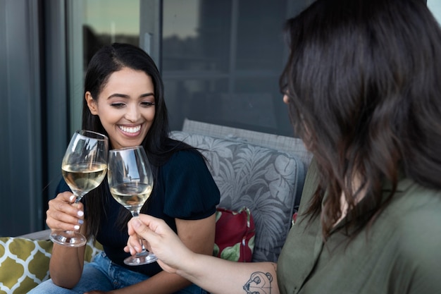Amiche sorridenti che trascorrono del tempo insieme e bevono vino su una terrazza