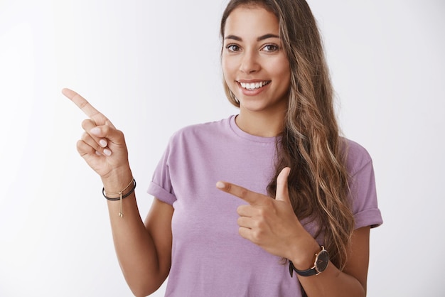 Amichevole ragazza sorridente che punta il dito di lato