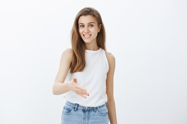 Amichevole ragazza sorridente piacere di conoscerti, allungare la mano per la stretta di mano, presentarsi