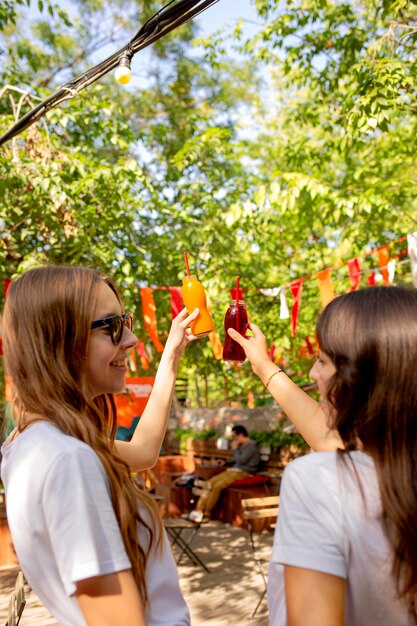 Amici a metà colpo che tengono le bottiglie di succo di frutta fresco nel parco