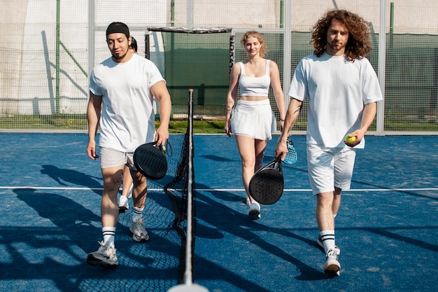 Amici a tutto campo che giocano a paddle tennis