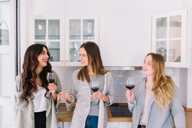 Amici allegri che bevono vino in cucina