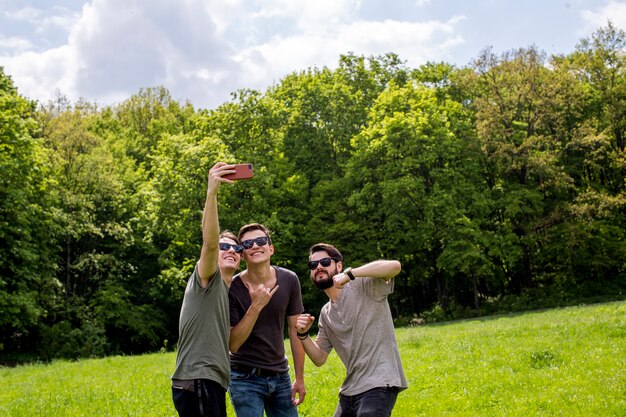 Amici allegri che prendono selfie sulla radura