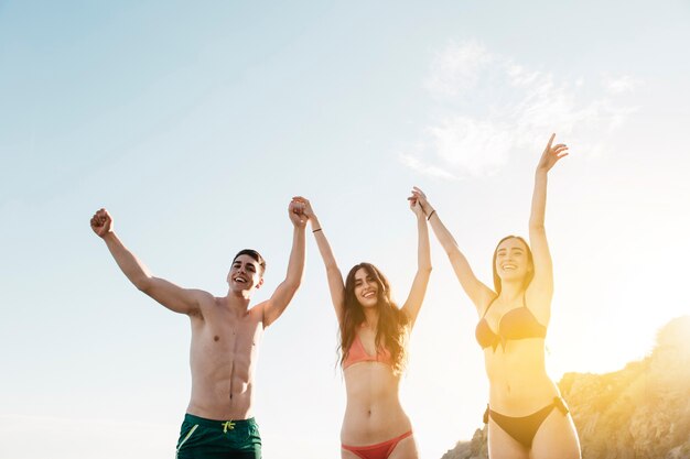 Amici che alzano le braccia in spiaggia