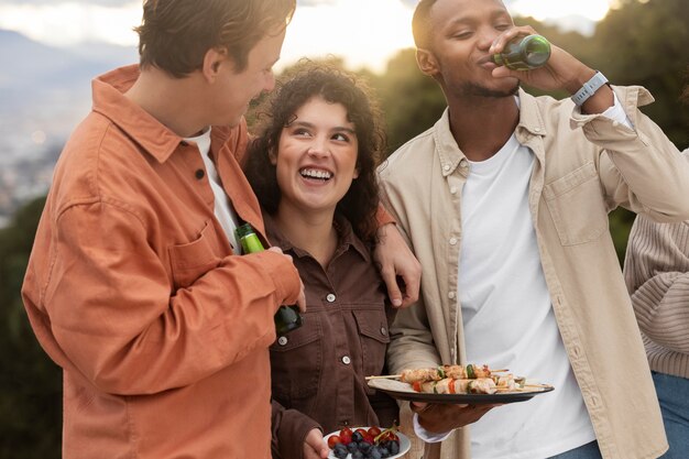 Amici che bevono birra e mangiano barbecue durante la festa all'aperto