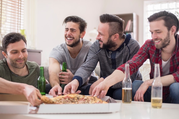 Amici che bevono birra e mangiano pizza