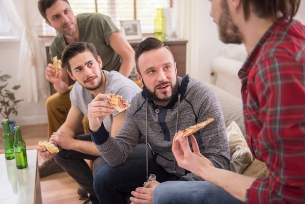 Amici che bevono birra e mangiano pizza