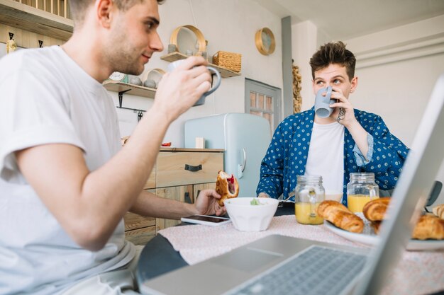 Amici che bevono caffè a guardare l&#39;altro seduti con colazione sul tavolo