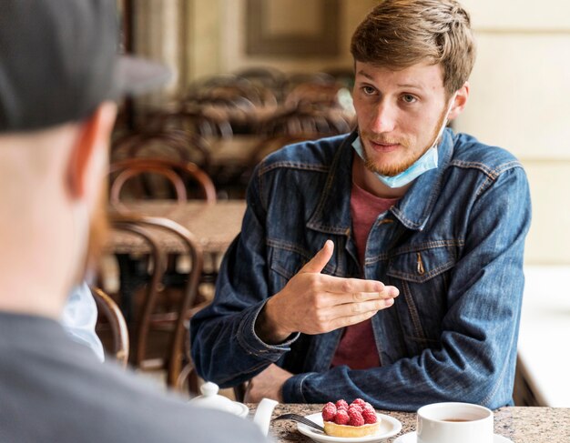 Amici che chiacchierano al ristorante con maschere facciali