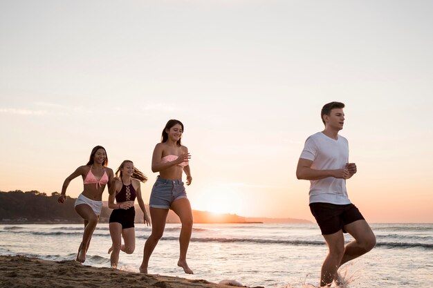 Amici che corrono insieme sulla spiaggia