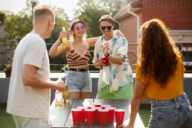 Amici che giocano a beer pong al tiro medio della festa