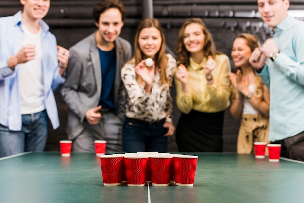 Amici che godono di birra pong sul tavolo al bar