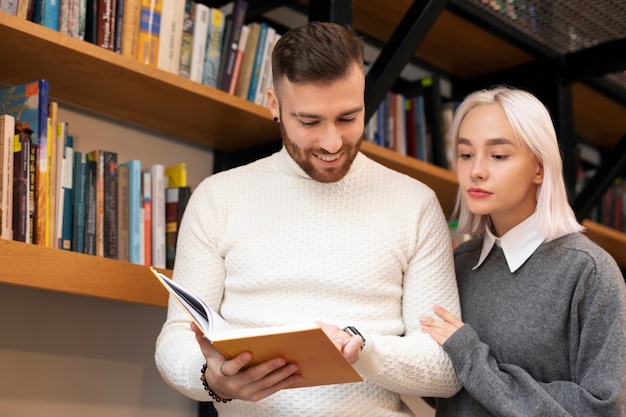 Amici che guardano il libro in una biblioteca