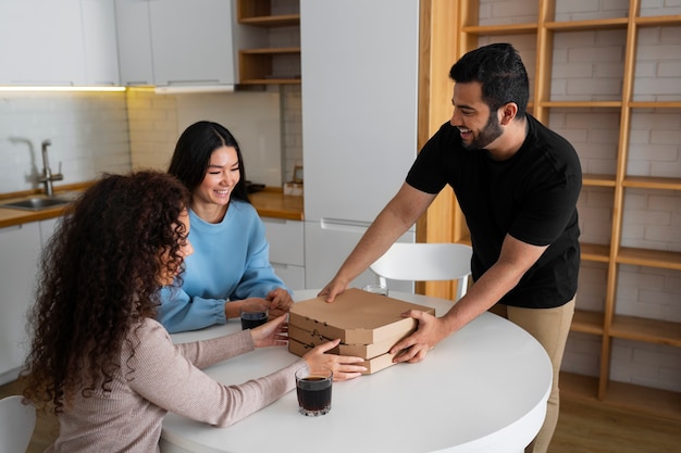 Amici che mangiano pizza a casa insieme